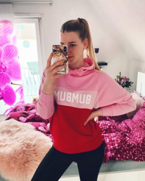 ein spiegelselfie von benita in ihrem schlafzimmer. sie traegt einen rosa-roten hoodie von bumbum