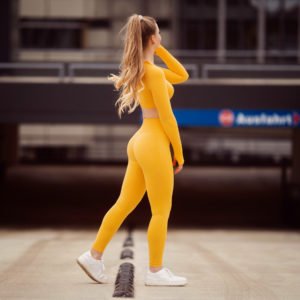 benita steht vor einer parkhausauffahrt in einem bielefelder parkhaus und traegt ein gelbes sportoutfit von gymshark