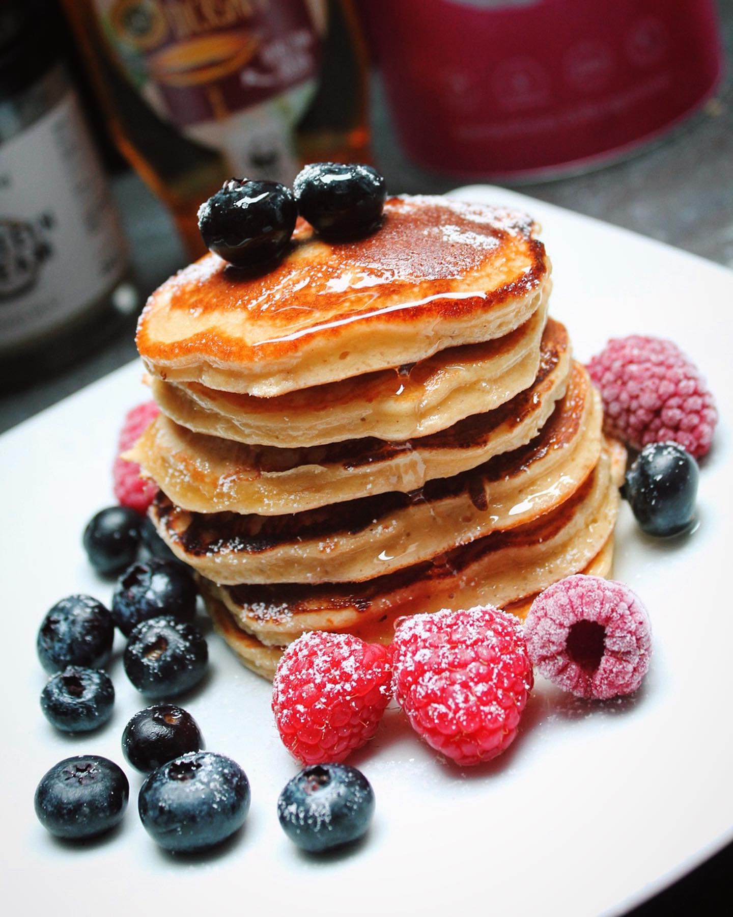 zuckerfreie protein pancakes getoppt mit puderxucker, himbeeren und heidelbeeren